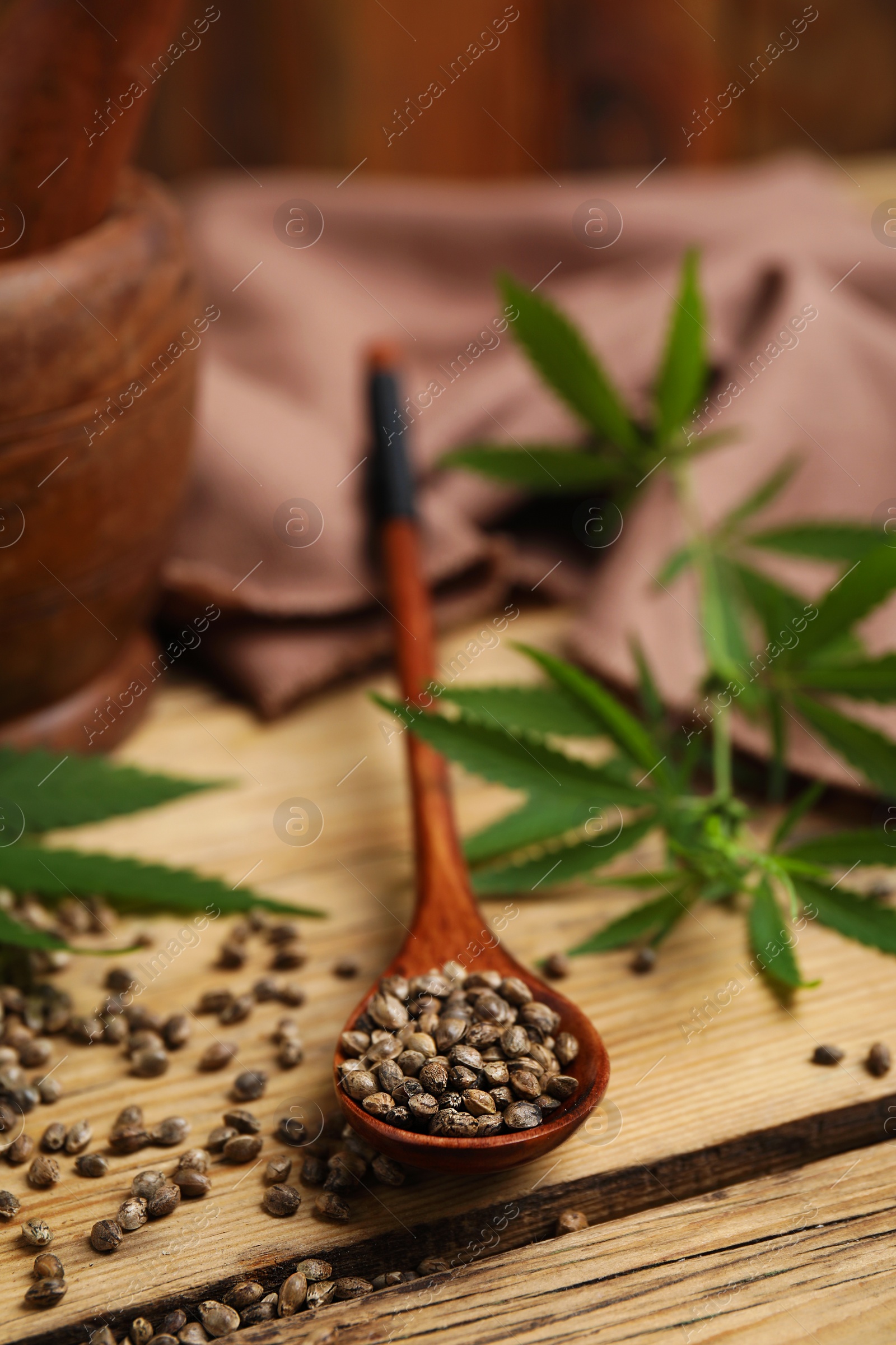 Photo of Organic hemp seeds and leaves on wooden table. Space for text