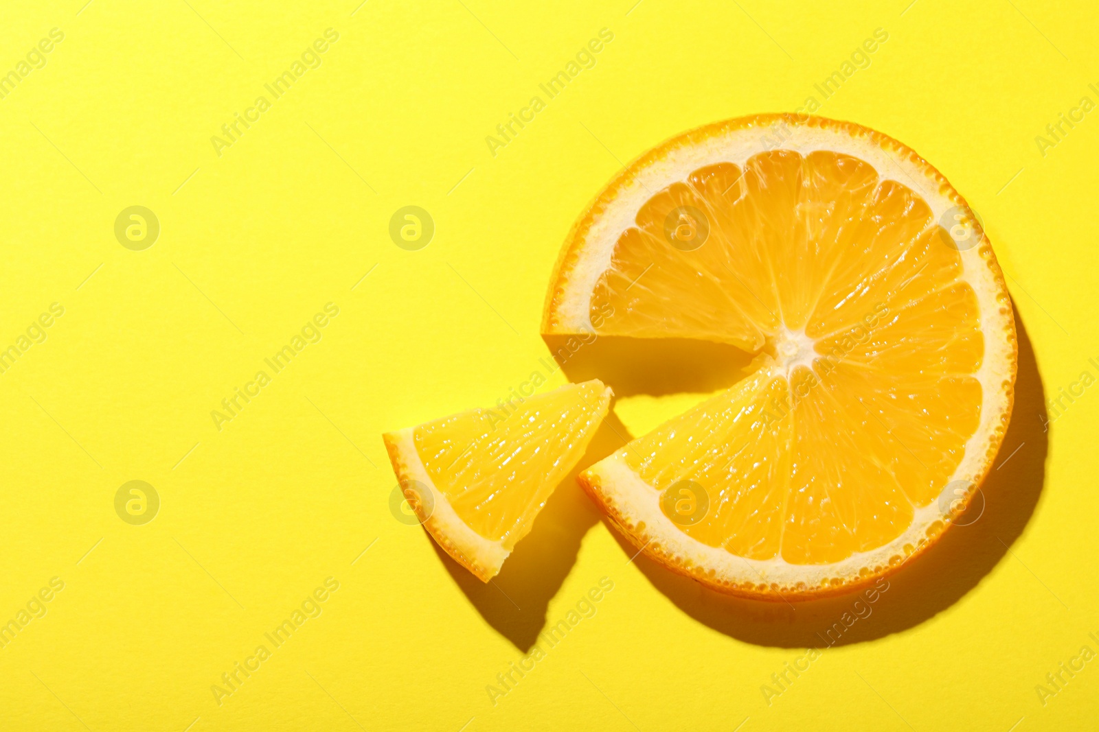 Photo of Slices of juicy orange on yellow background, top view. Space for text