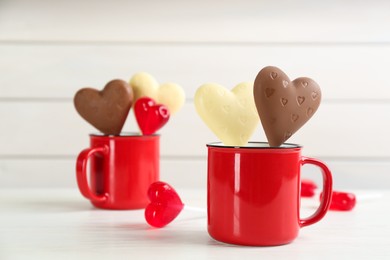 Photo of Heart shaped lollipops made of chocolate and sugar syrup on white table, space for text