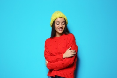 Photo of Young woman in warm sweater and hat on color background. Celebrating Christmas