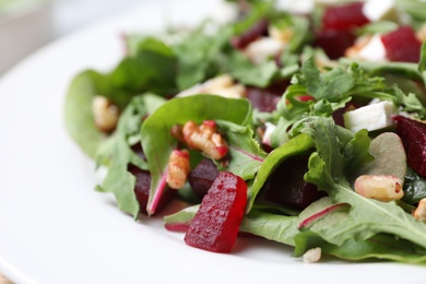 Photo of Delicious beet salad with arugula and walnuts on plate, closeup view