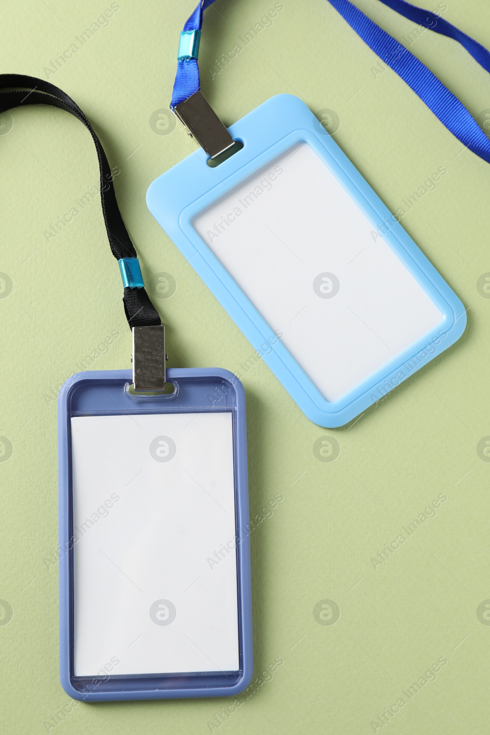 Photo of Blank badges with strings on light green background, top view