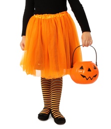 Photo of Cute little girl with pumpkin candy bucket wearing Halloween costume on white background, closeup