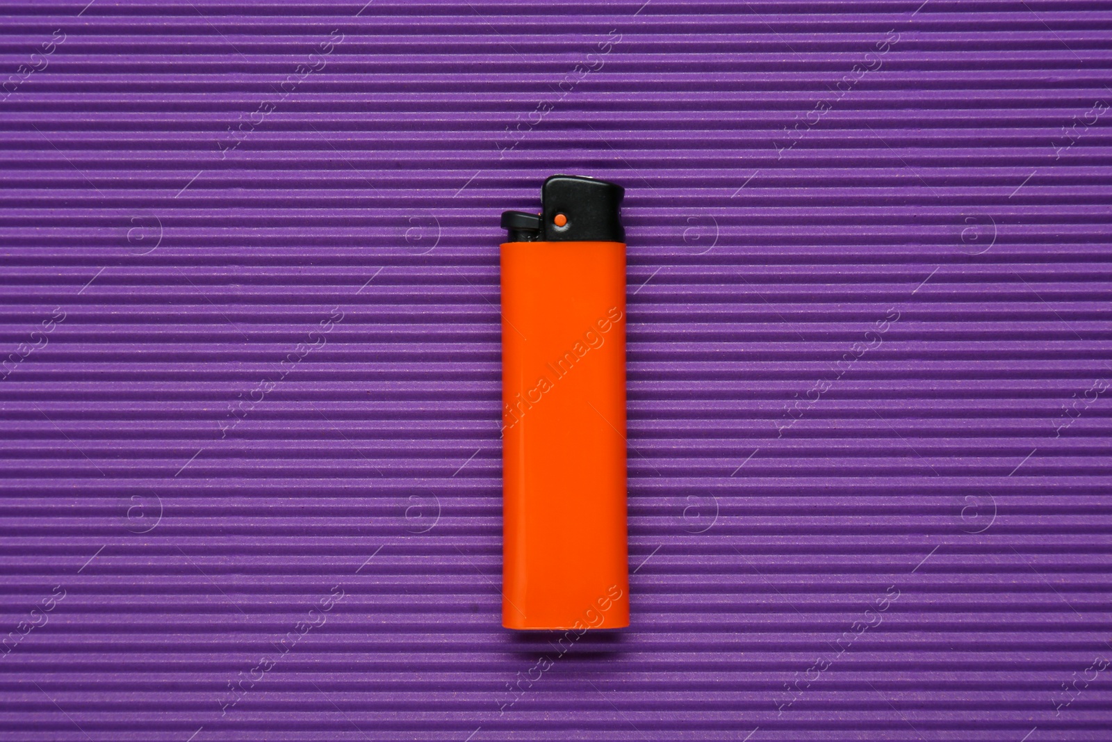 Photo of Stylish small pocket lighter on purple corrugated fiberboard, top view