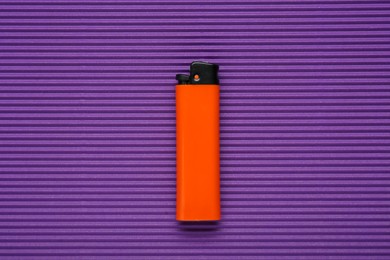 Photo of Stylish small pocket lighter on purple corrugated fiberboard, top view
