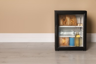 Mini bar filled with food and drinks near beige wall indoors, space for text