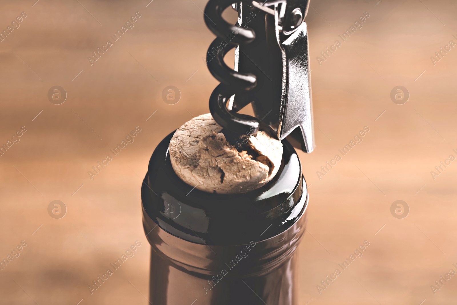 Image of Opening wine bottle with corkscrew on blurred background, closeup