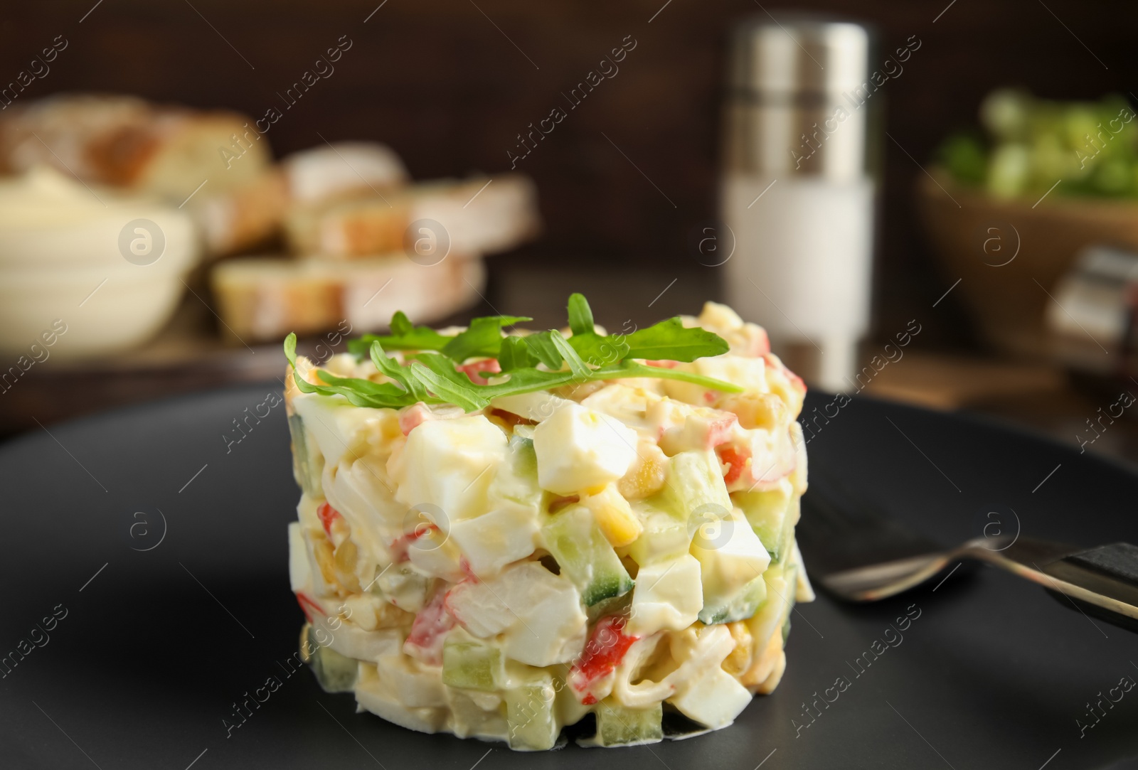 Photo of Delicious salad with crab sticks on black plate, closeup