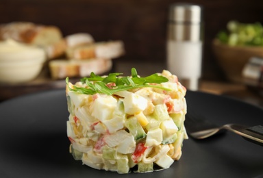 Photo of Delicious salad with crab sticks on black plate, closeup