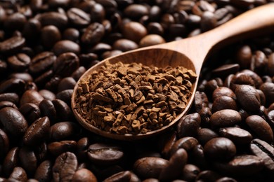 Photo of Spoon with instant coffee on roasted beans, closeup