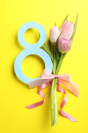 Photo of 8 March card design with tulips on yellow background, flat lay. International Women's Day