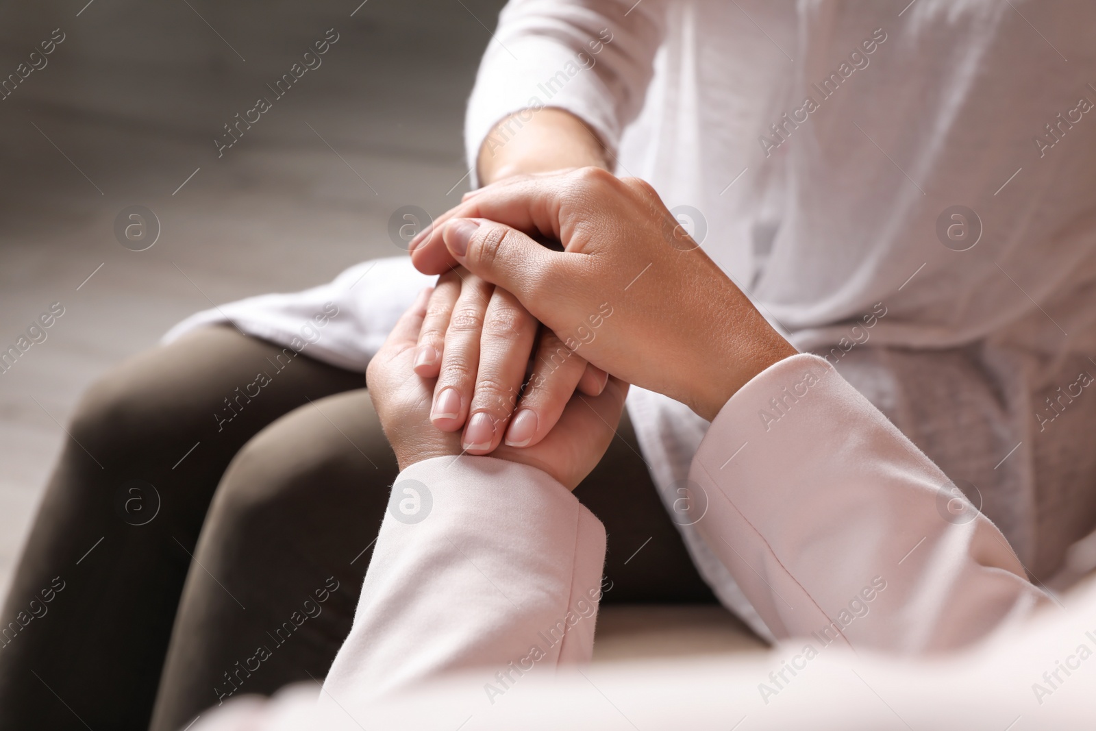 Photo of Women holding hands indoors, closeup. Concept of support and help