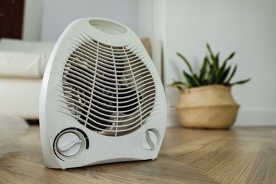 Modern electric fan heater on floor at home. Space for text