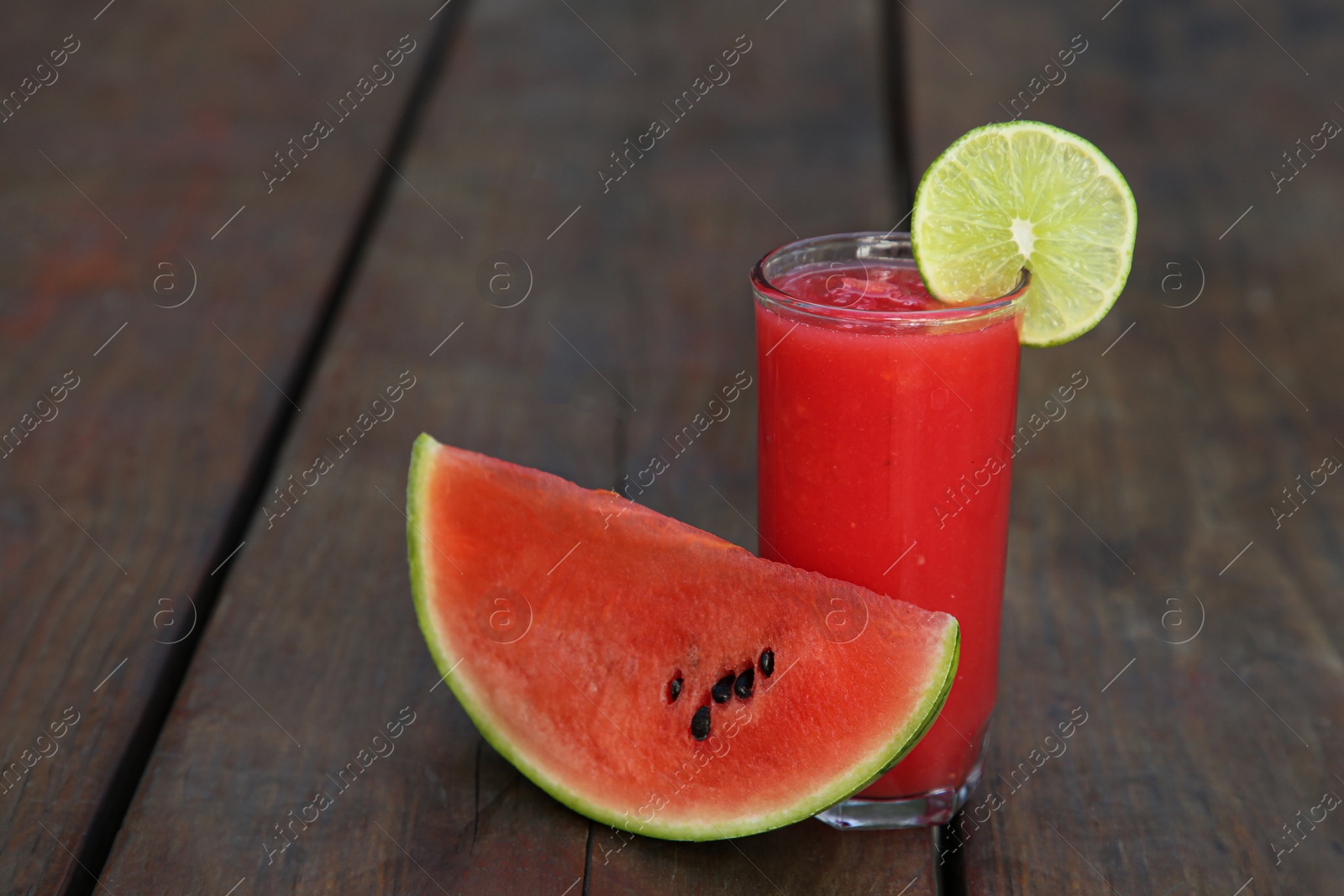 Photo of Delicious watermelon drink in glass on wooden table