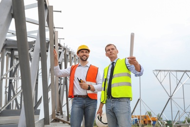 Professional engineers working on installation of electrical substation outdoors