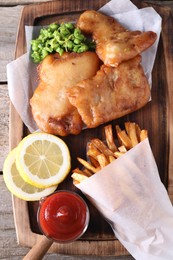 Tasty fish, chips, sauce and peas on wooden table, top view