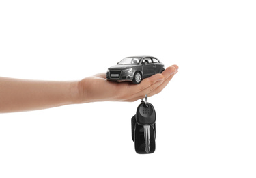 Photo of Woman holding key and miniature automobile model on white background, closeup. Car buying