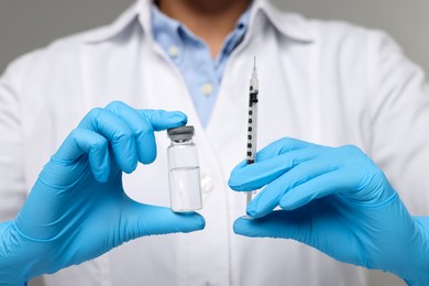 Photo of Doctor holding syringe and glass vial, closeup view