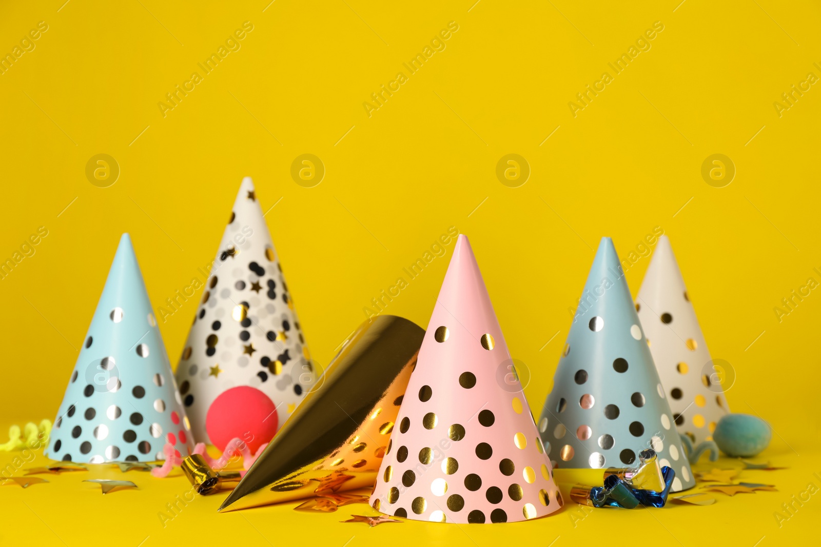 Photo of Many colorful party hats and festive items on yellow background