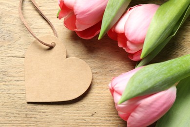 Happy Mother's Day. Beautiful tulips with blank heart shaped card on wooden table, closeup