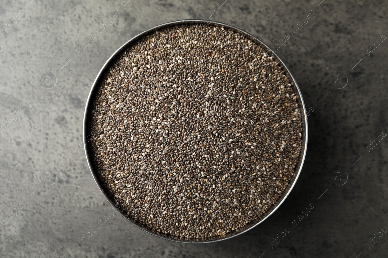Photo of Bowl with chia seeds on grey table, top view