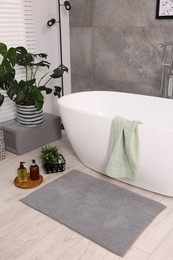 Stylish bathroom interior with soft bath mat and tub