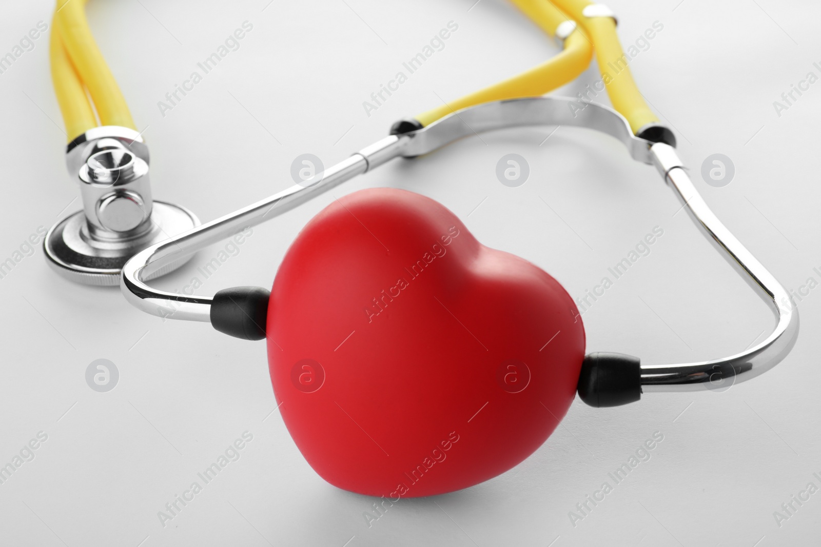 Photo of Red heart with stethoscope on white background, closeup