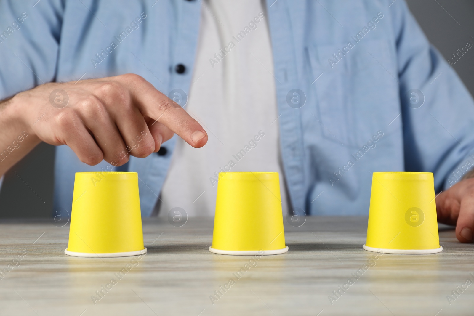 Photo of Man playing shell game at wooden table, closeup