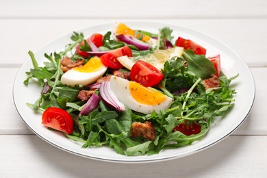 Delicious salad with boiled eggs, vegetables and bacon on white wooden table, closeup