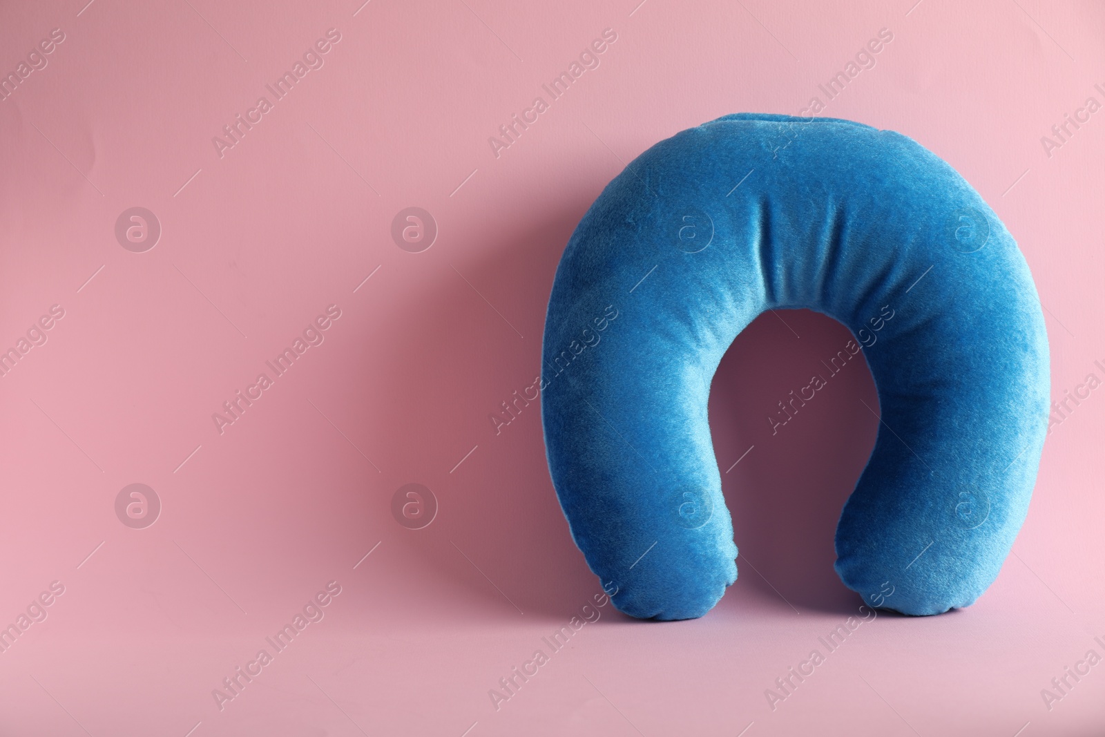 Photo of Light blue travel pillow on pink background, space for text