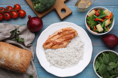 Photo of Grilled chicken breast and rice served with vegetables on light blue wooden table, flat lay