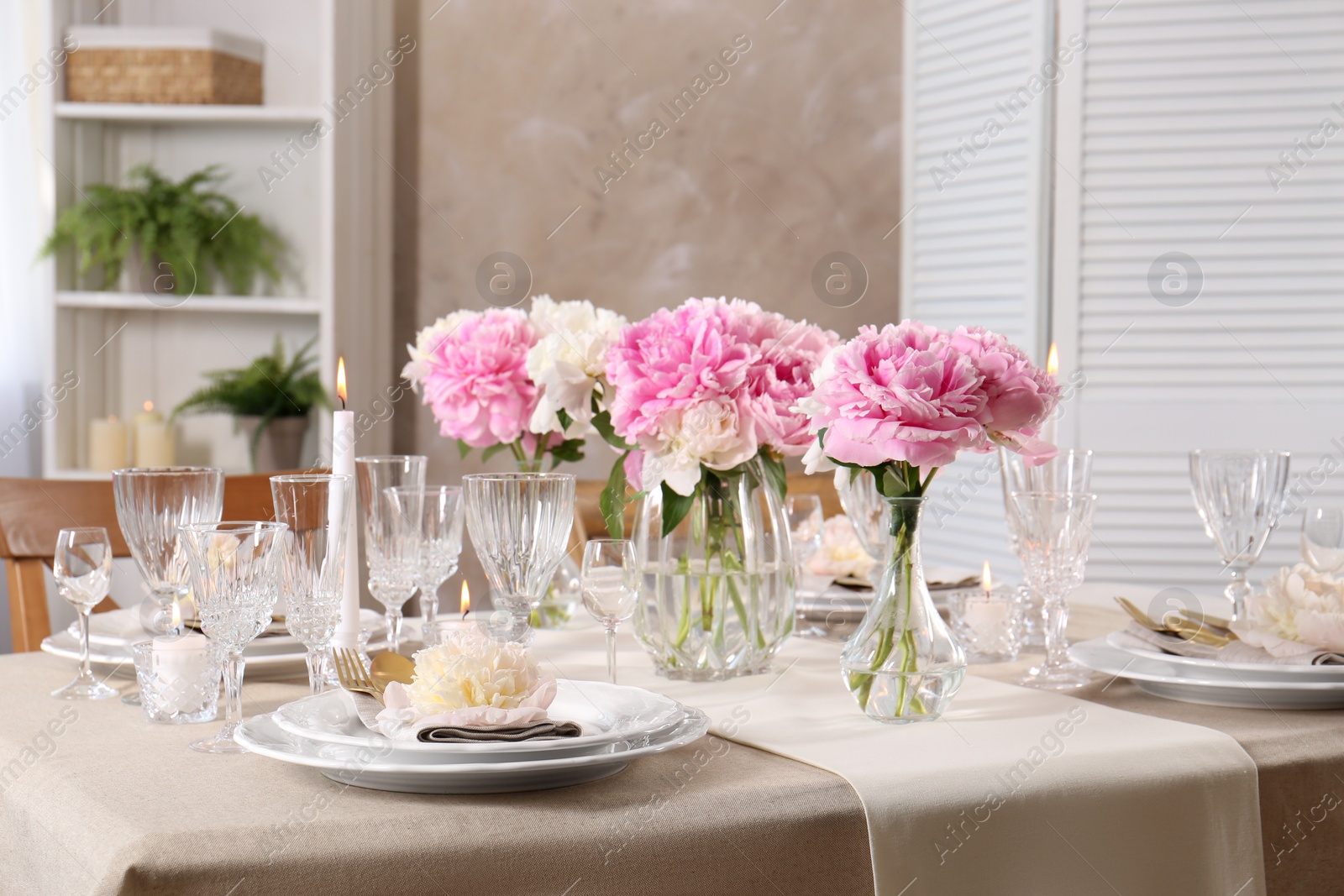 Photo of Stylish table setting with beautiful peonies and burning candles indoors