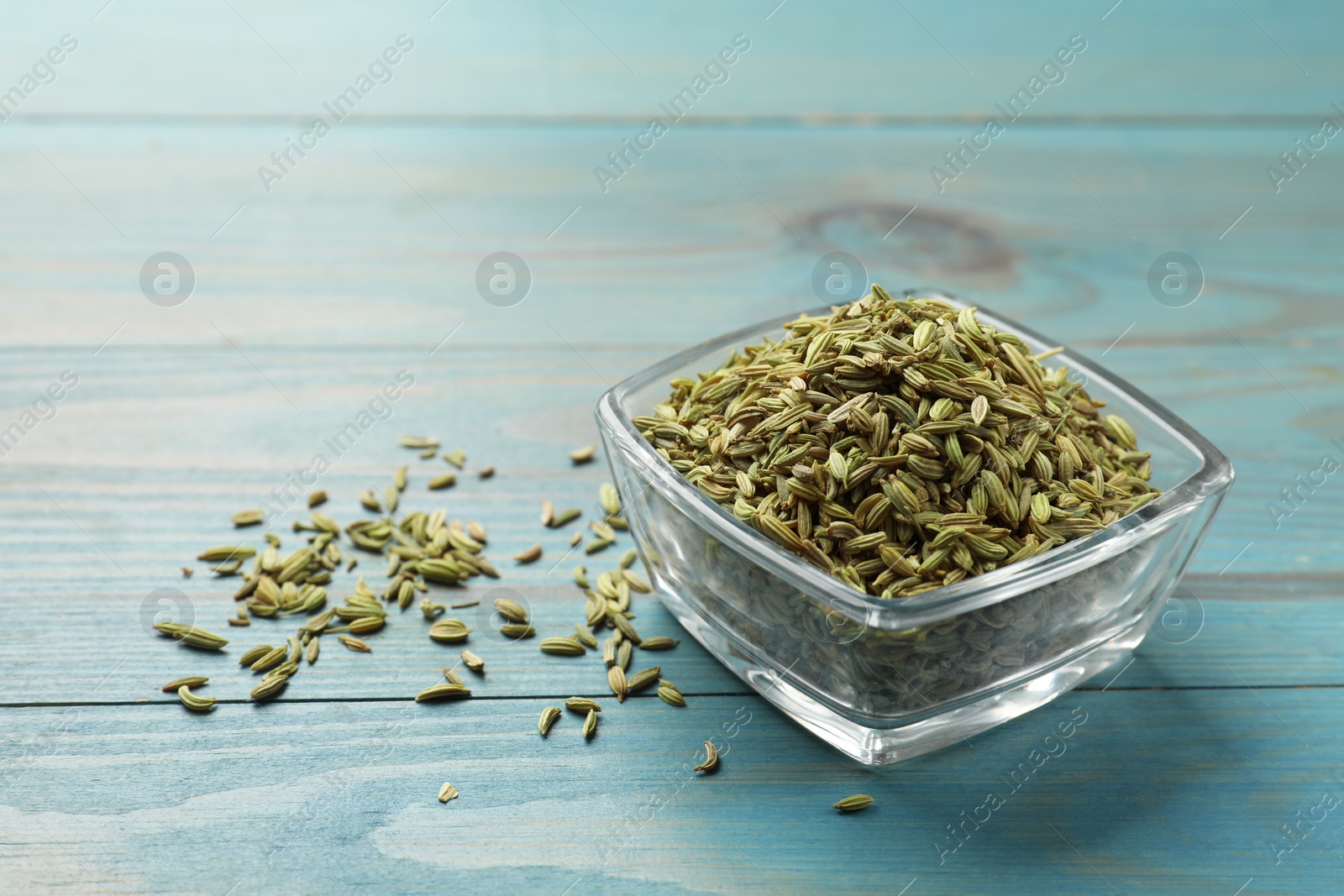Photo of Fennel seeds in bowl on light blue wooden table, space for text
