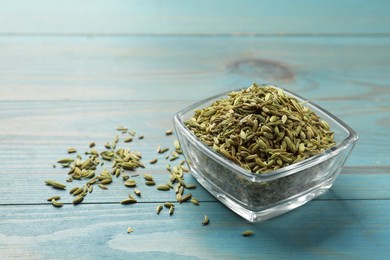 Photo of Fennel seeds in bowl on light blue wooden table, space for text