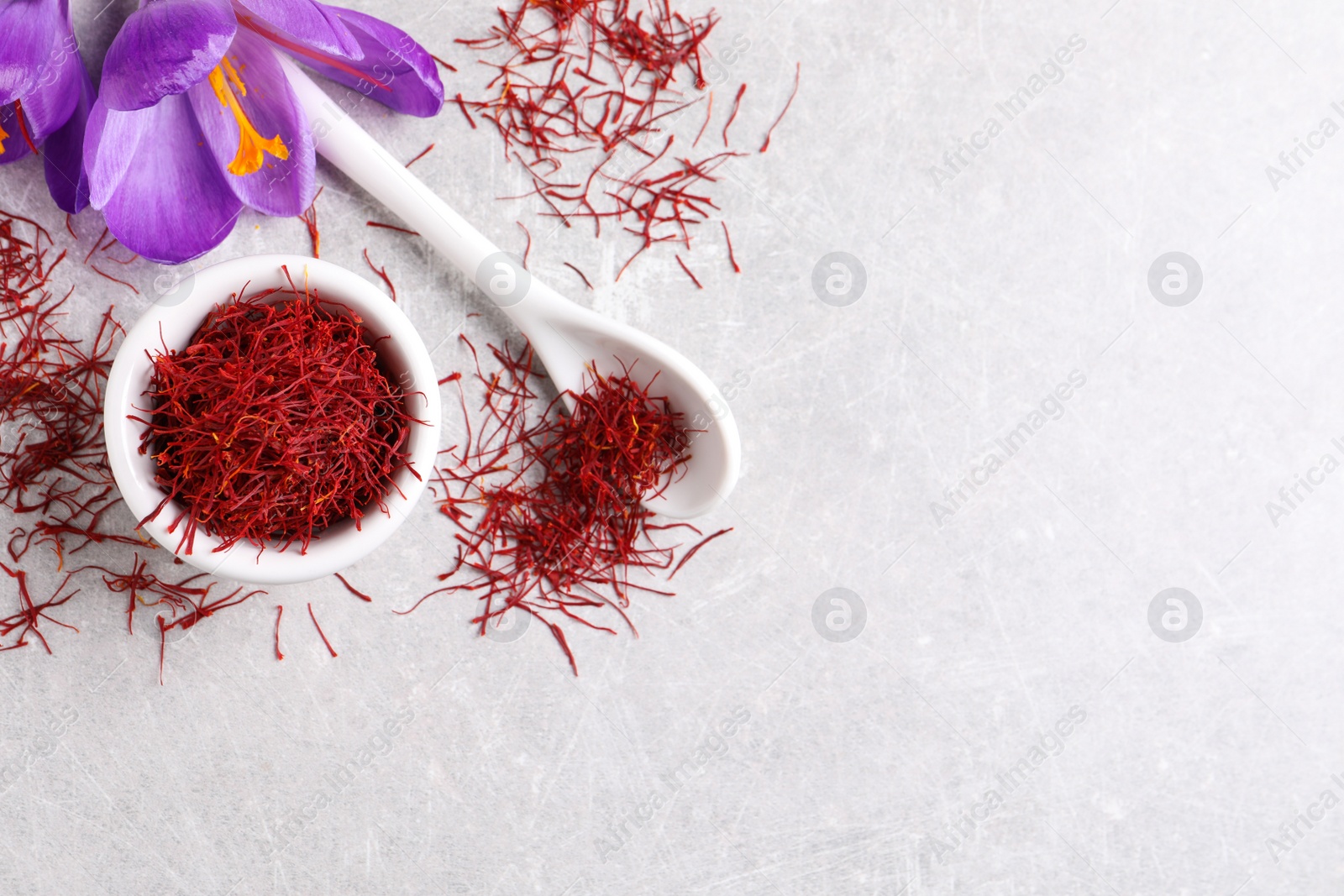 Photo of Dried saffron and crocus flowers on grey table, flat lay. Space for text