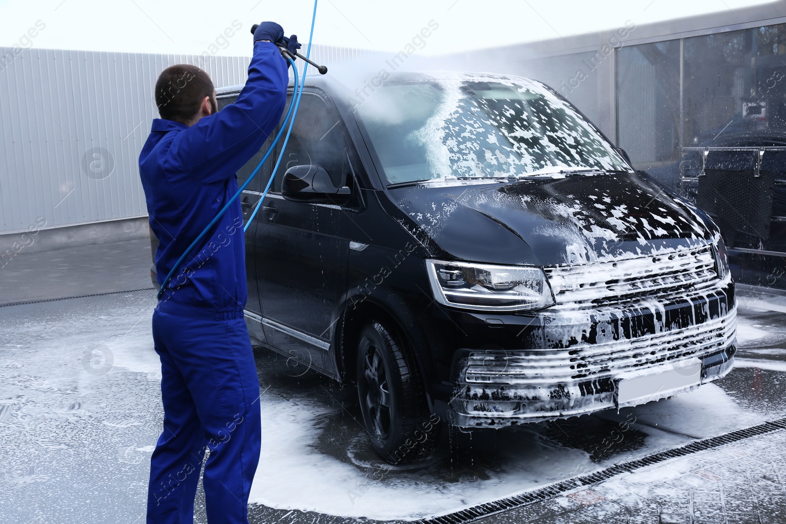 Photo of Worker cleaning automobile with high pressure water jet at car wash