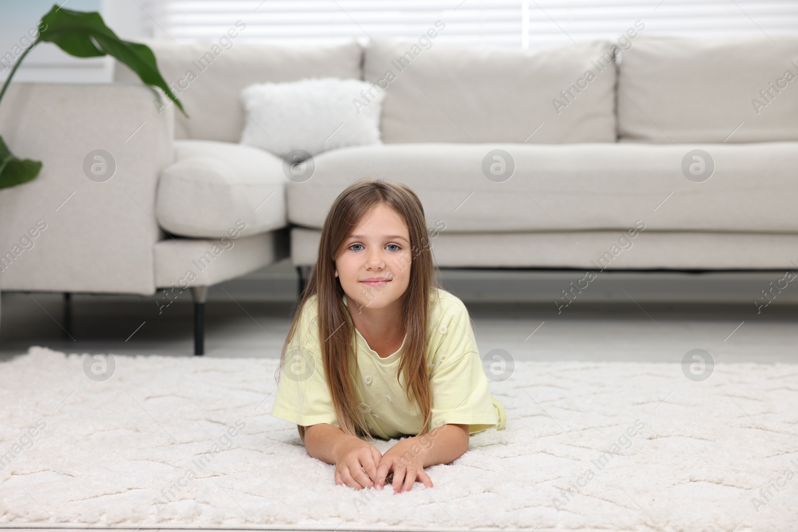 Photo of Little girl on carpet near sofa at home