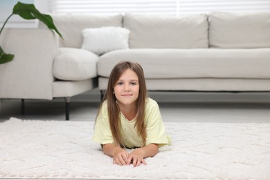 Little girl on carpet near sofa at home