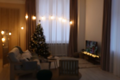 Photo of TV set, furniture and Christmas tree in stylish room, blurred view