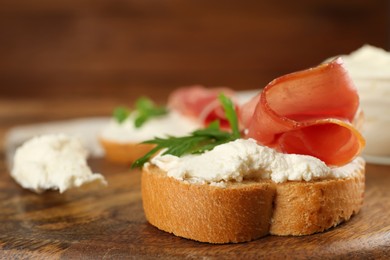 Delicious sandwich with cream cheese, jamon and parsley on wooden board, closeup