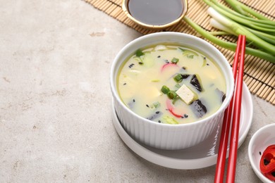 Photo of Bowl of delicious miso soup with tofu served on light grey table. Space for text