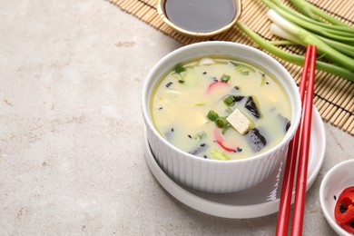 Bowl of delicious miso soup with tofu served on light grey table. Space for text