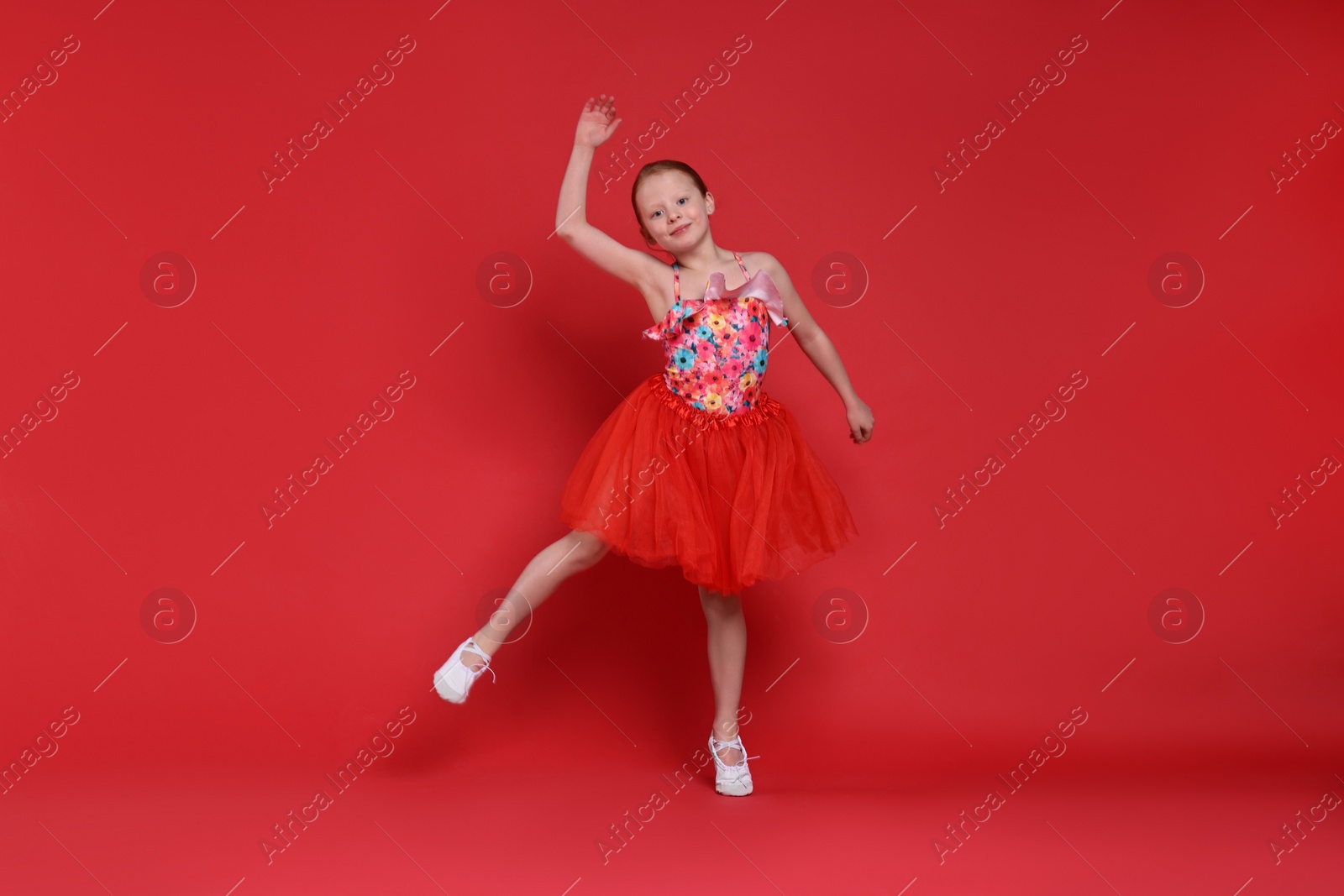 Photo of Cute little girl dancing on red background