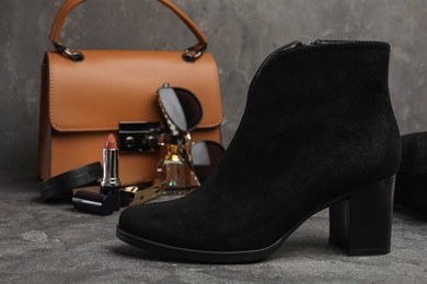 Stylish black female boot on grey stone table