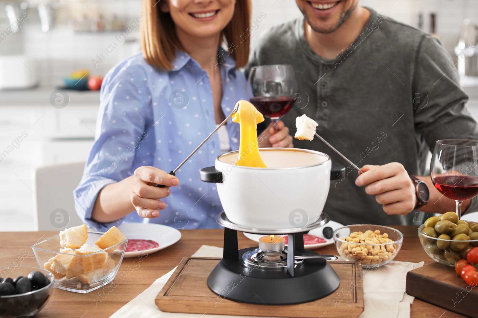 Photo of Happy couple enjoying fondue dinner at home, closeup