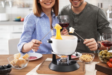 Happy couple enjoying fondue dinner at home, closeup