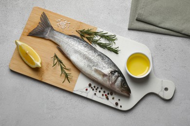 Sea bass fish and ingredients on light grey table, top view