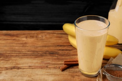 Photo of Tasty banana smoothie and ingredients on wooden table. Space for text