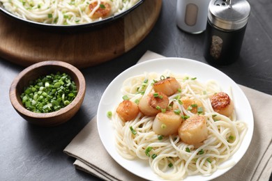 Photo of Delicious scallop pasta with green onion served on grey table