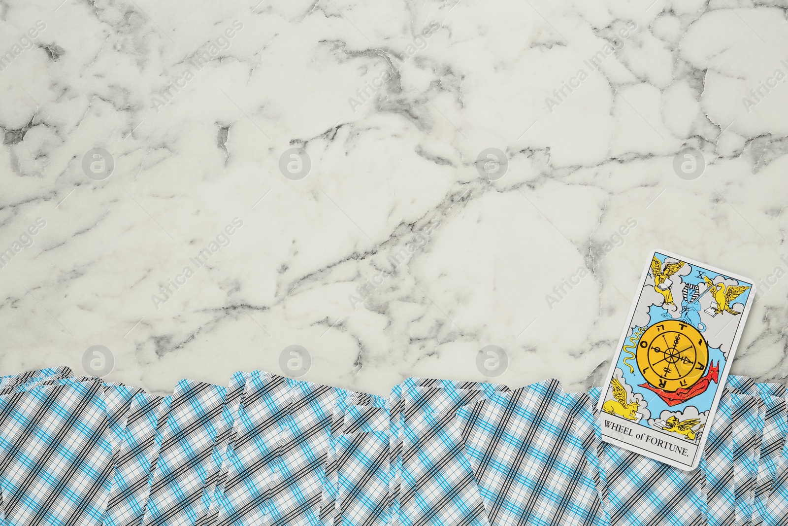 Photo of The Wheel of Fortune and other tarot cards on white marble table, flat lay. Space for text